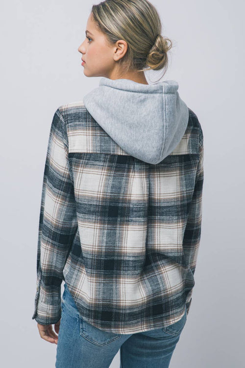 A woman shown from the back wearing a plaid hooded flannel shirt with a light gray heathered hood, paired with blue jeans, against a plain light gray studio background.