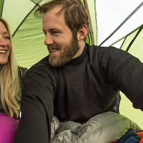 Two people inside a tent, one taking a selfie.