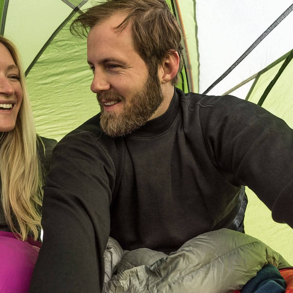 Two people inside a tent, one taking a selfie.