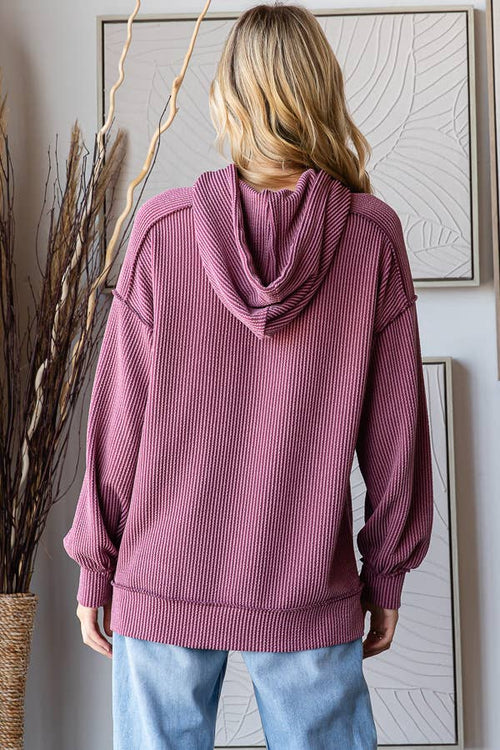 Person wearing a maroon hoodie with a neutral background