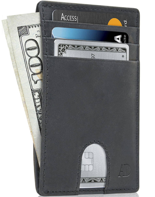 A slim black leather cardholder wallet shown open, filled with cash and sample credit cards, on a white background.