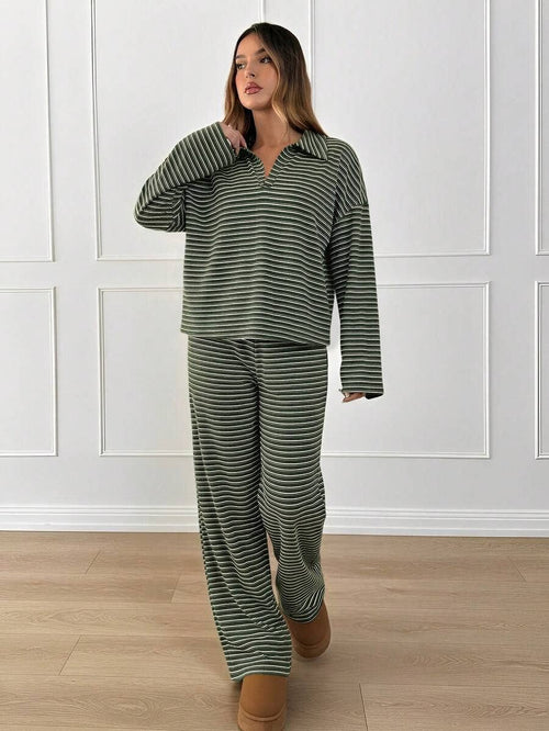 Woman wearing a green and white striped pajama set in a room with white paneled walls.
