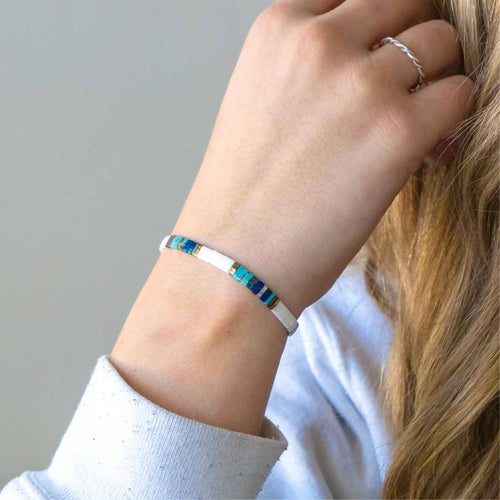 Person wearing a bracelet with blue stones on a neutral background