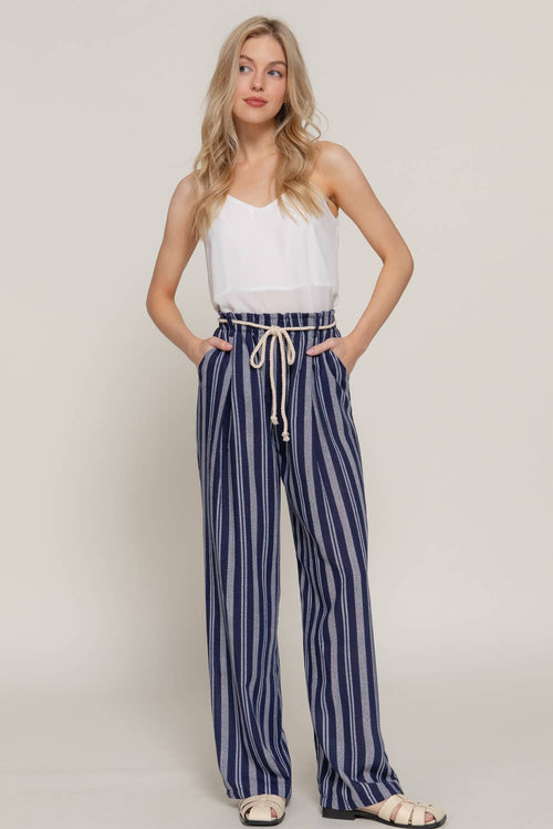 Woman wearing a white top and blue striped pants on a plain background