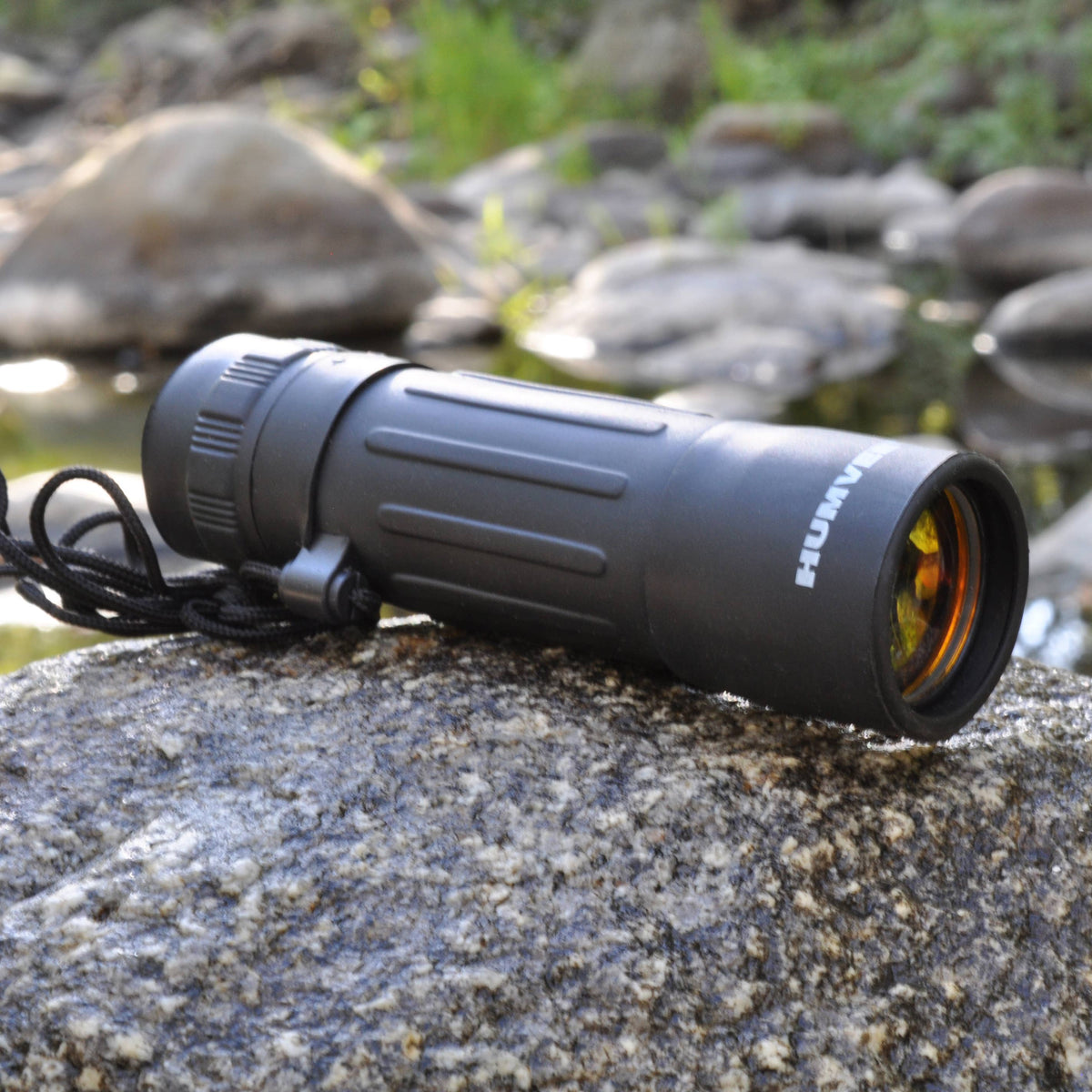 Black monocular on a rock with a natural background