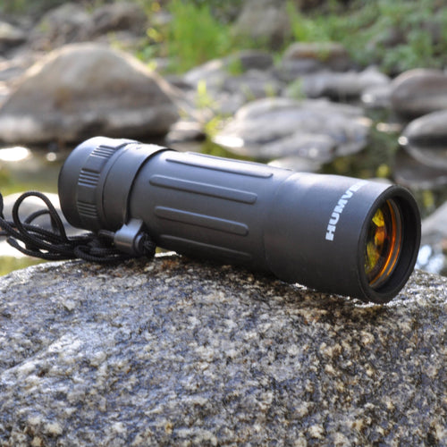 Black monocular on a rock with a natural background