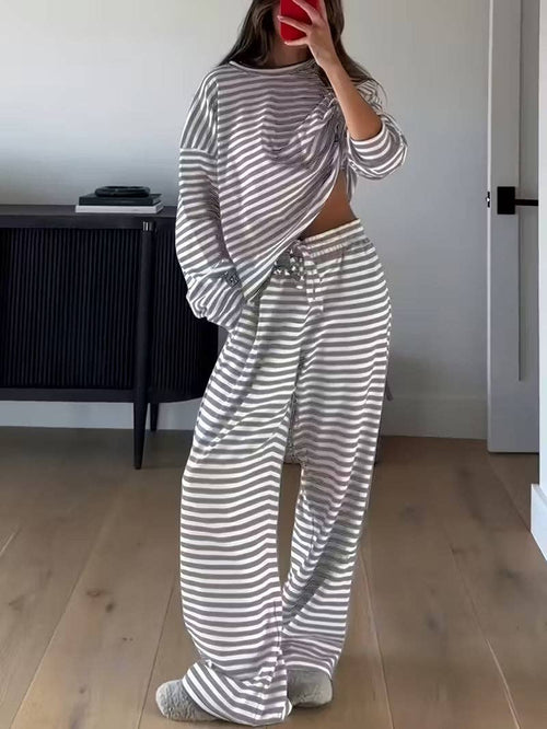Person wearing a gray and white striped outfit in a room with a desk and door.