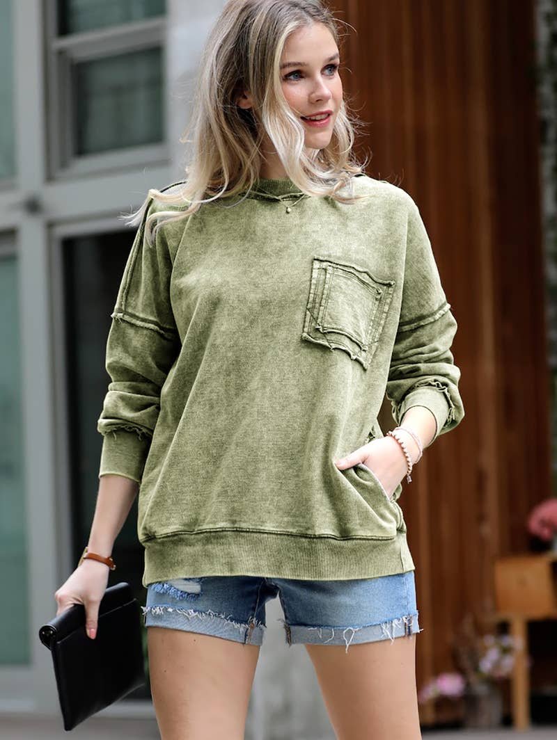 Woman wearing a green hoodie with a pocket, standing outdoors.