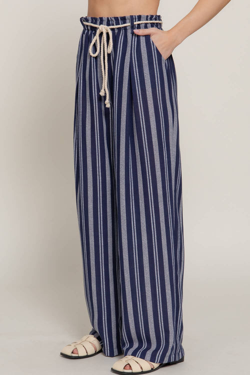 Navy and white striped pants worn by a person on a plain background