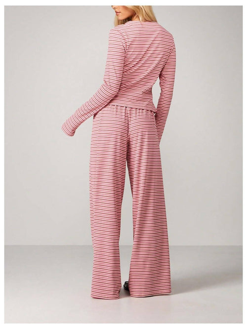 A woman shown from the back wearing a matching long-sleeve top and wide-leg pants set in a dusty pink and white stripe pattern, set against a plain light gray studio background.