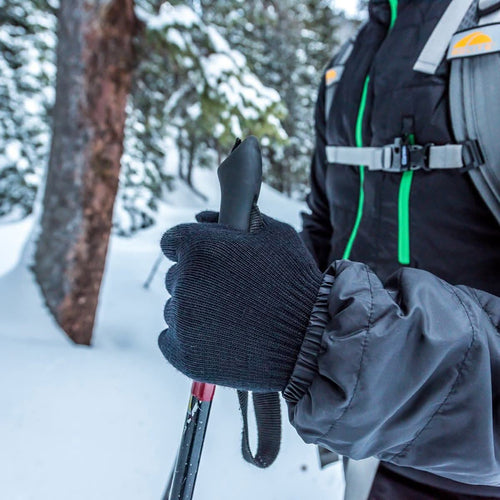 Person skiing in a snowy forest with a backpack