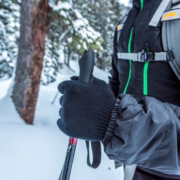 Person skiing in a snowy forest with a backpack