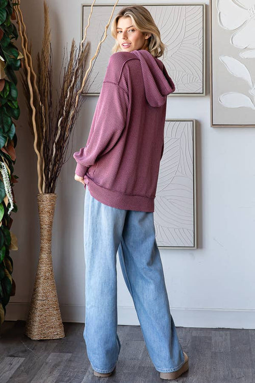 Person wearing a pink hoodie and blue jeans standing in a room with decorative elements.