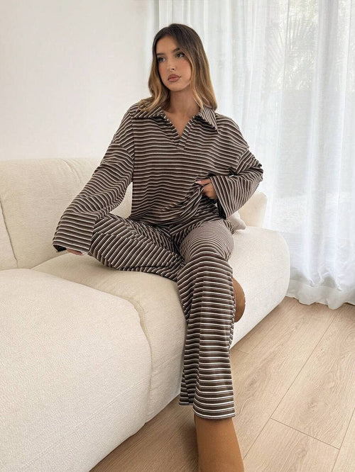 Woman in a striped outfit sitting on a white couch with a neutral background