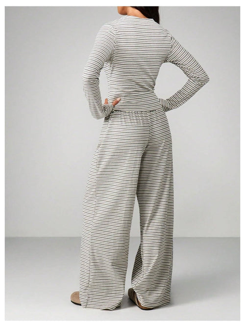 Person wearing a gray and white striped outfit with wide-leg pants on a light gray background