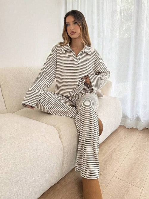 Woman wearing a striped pajama set sitting on a couch.