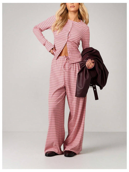 Woman wearing a pink and white striped outfit with a jacket on a gray background