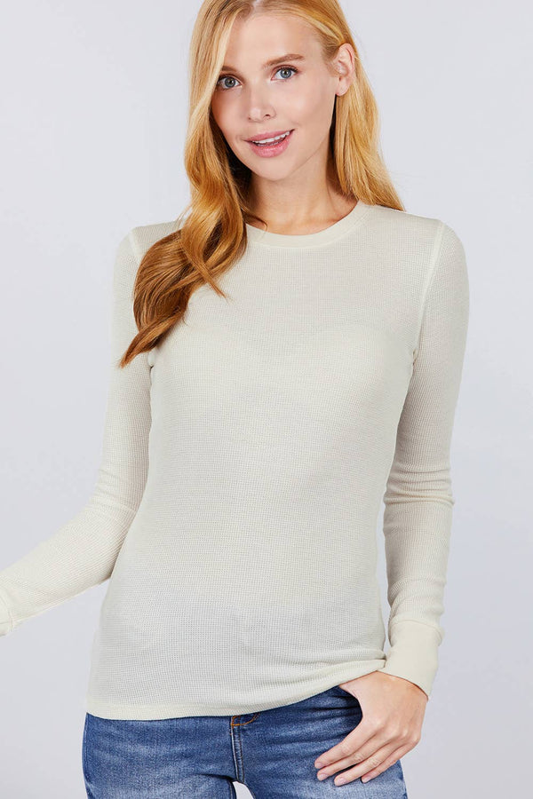Woman wearing a light gray long-sleeve top against a plain background