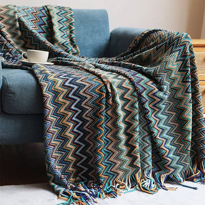 Patterned blanket draped over a blue armchair with a cup on a table.