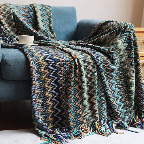 Patterned blanket draped over a blue armchair with a cup on a table.