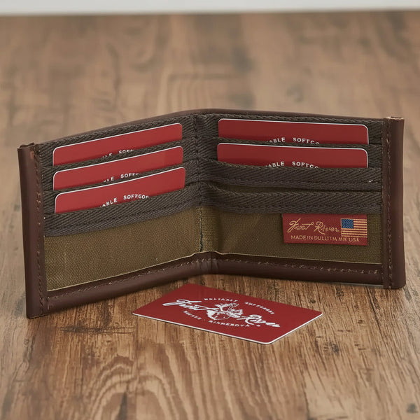 Brown leather wallet with canvas interior, red card slots, and 'Made in USA' label on wooden surface