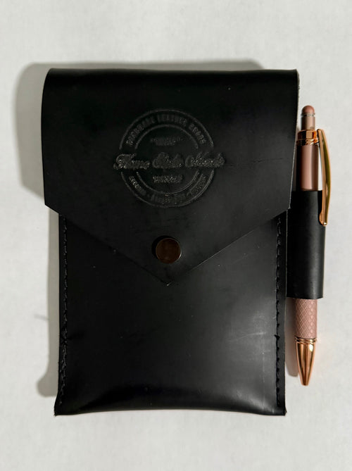 A black leather pen pouch with a snap button closure and debossed logo, shown next to a rose gold and black pen on a white background.