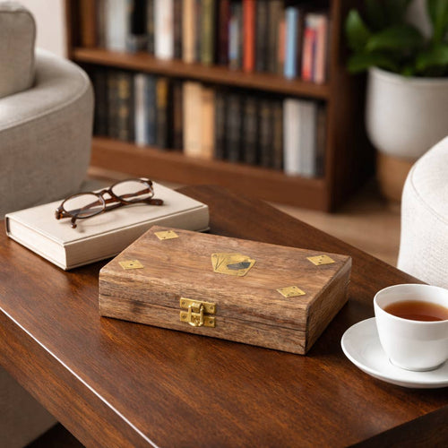  Card Game Sets Wooden box with gold accents on a wooden table with a book, glasses, and a cup of tea.