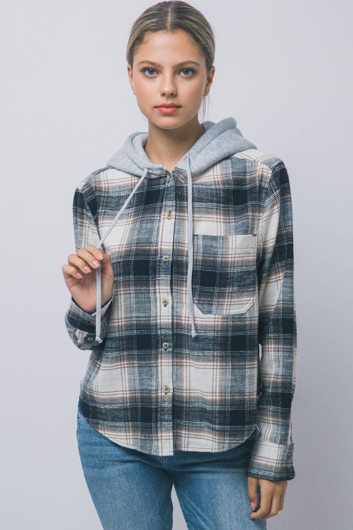 Hooded Flannel Shirt A woman modeling a hooded button-up shirt with a blue, gray, and white plaid pattern, featuring a light gray hood and drawstrings, paired with blue jeans.