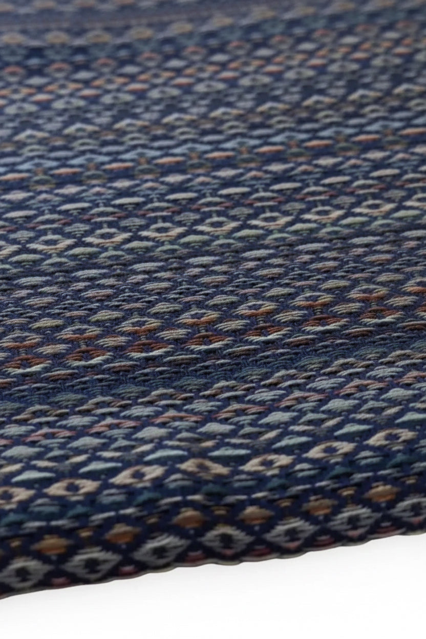 Close-up of a woven fabric with a blue and multicolor pattern on a plain background
