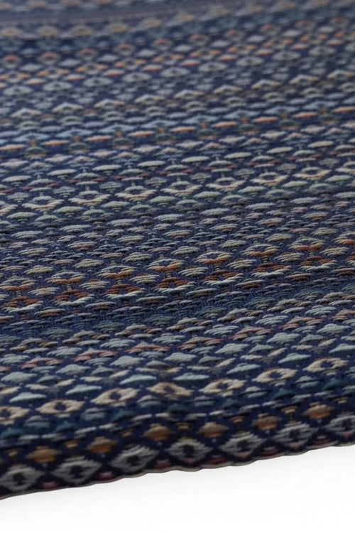 Close-up of a woven fabric with a blue and multicolor pattern on a plain background