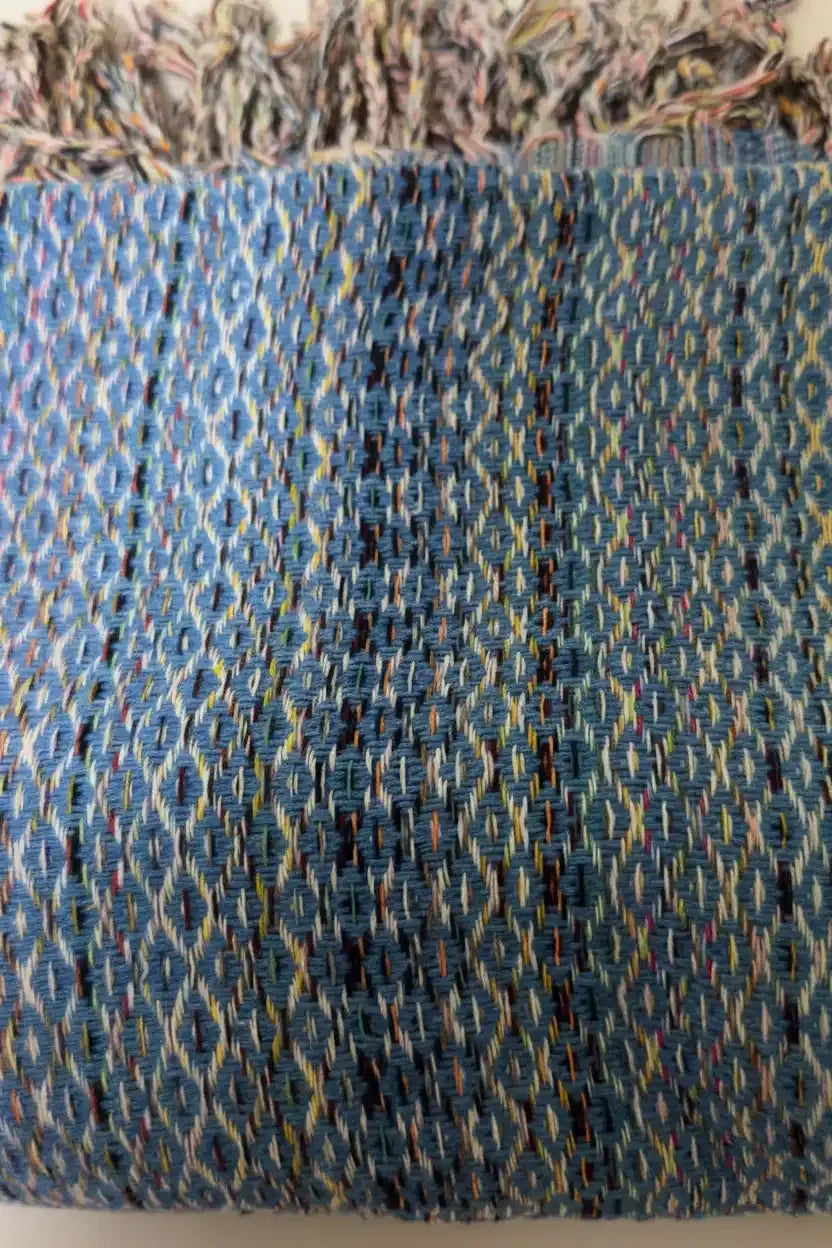 Close-up of a textured fabric with a blue and multicolor pattern