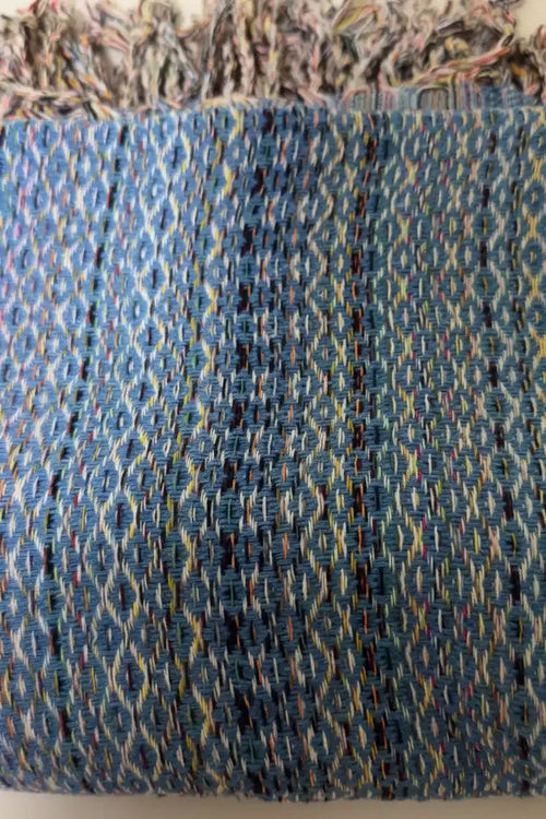 Close-up of a textured fabric with a blue and multicolor pattern