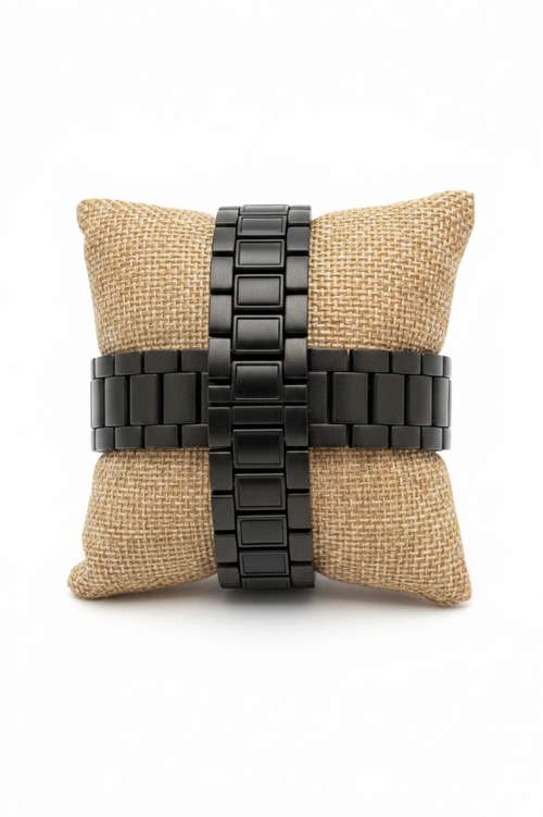 Black watch strap on a beige pillow against a white background