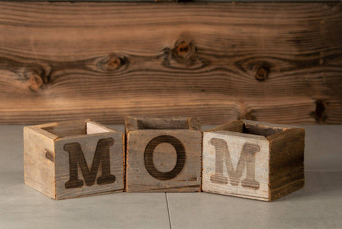 Wooden blocks spelling ' MOM' on a wooden background