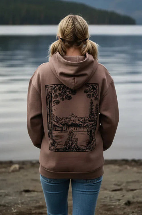 Oversized Pullover Hoodies Person wearing a brown hoodie with a nature-themed design, standing by a lake.