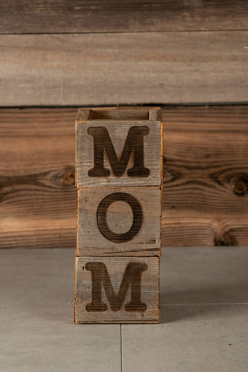 Wooden block with 'MOM' letters on a wooden background