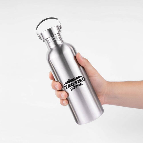 Silver water bottle with 'Tactiko Survival' logo held by a hand on a light gray background