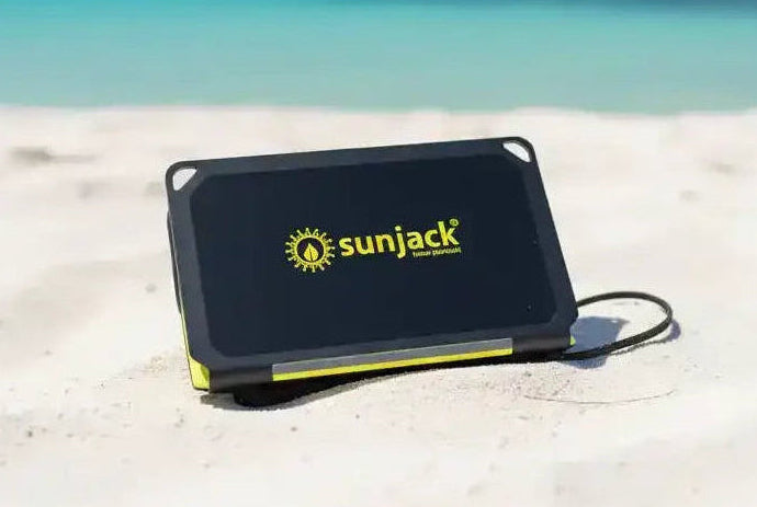 SunJack portable solar charger on sandy beach with ocean view