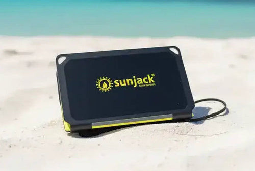 SunJack portable solar charger on sandy beach with ocean view