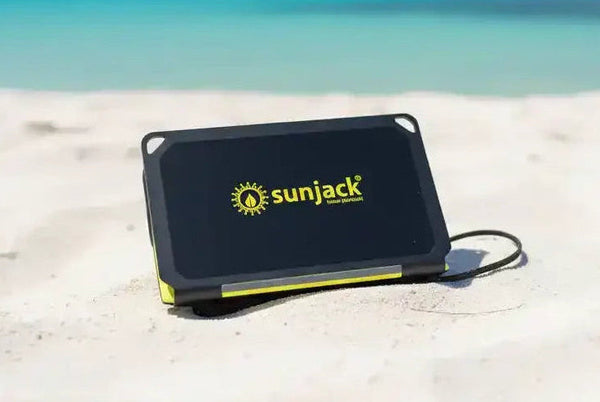 SunJack portable solar charger on sandy beach with ocean view