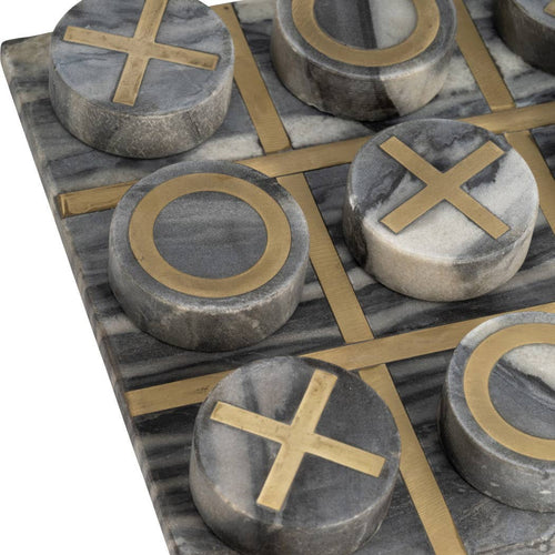 A close-up of a marble game board with round gray and white stone tokens marked with gold-tone crosses and circles, arranged on a white background.