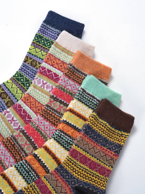 Six pairs of patterned crew socks arranged diagonally on a white background, showcasing various colorful Fair Isle and geometric stripe designs.