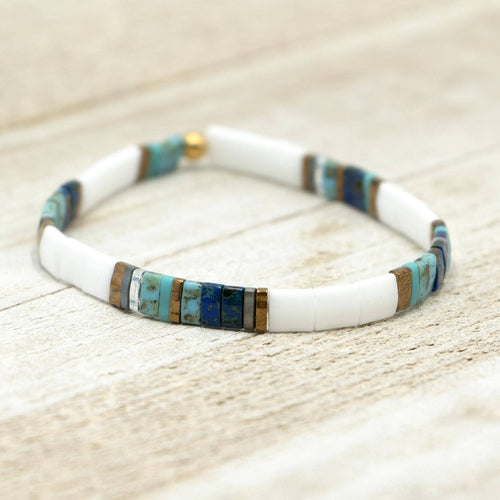 Bracelet with white, blue, and gold beads on a wooden surface