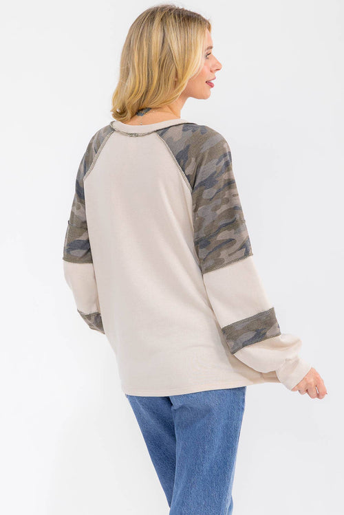 Woman wearing a beige and camouflage long-sleeve shirt on a white background