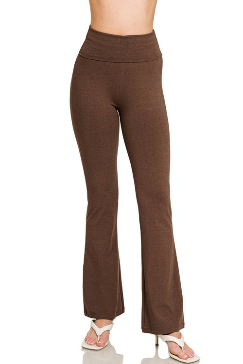 A person wearing high-waisted brown flare pants with white heeled sandals, shown from the waist down against a plain white background.