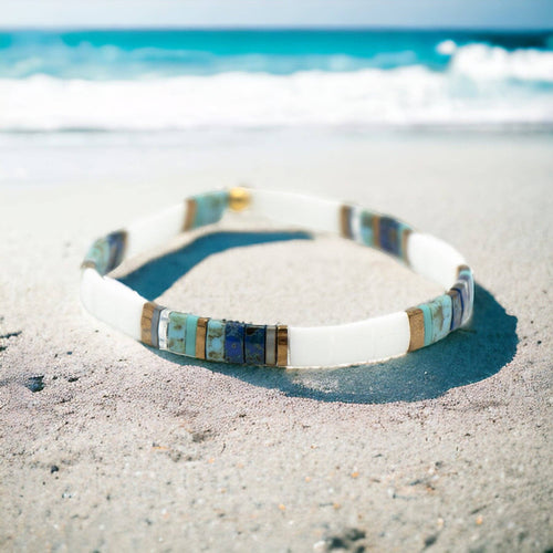 Multicolored bracelet on a sandy beach with ocean in the background