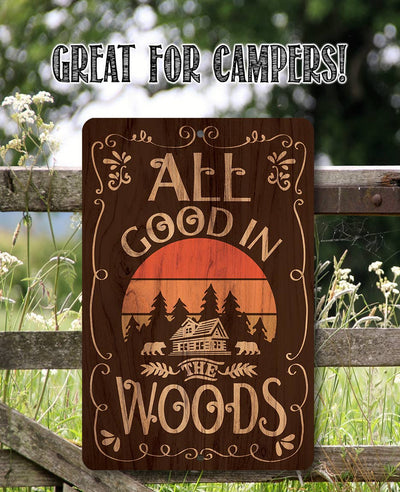 Wooden sign with 'All Good in the Woods' text and sunset design, placed outdoors.