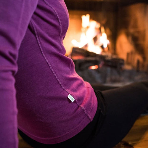 Person wearing a purple hoodie sitting in front of a fireplace
