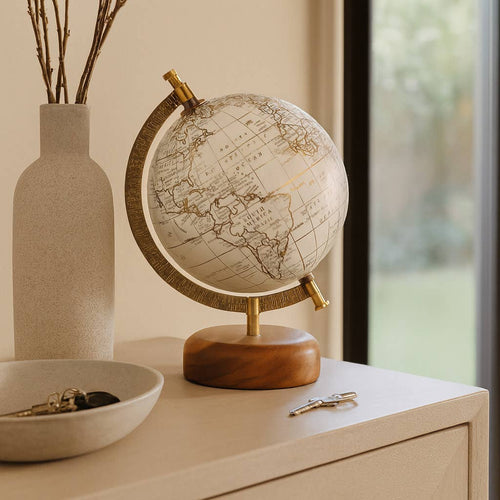 World globe on a wooden stand with a vase and keys in the background