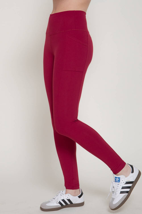 Red leggings worn by a person with white sneakers on a light gray background